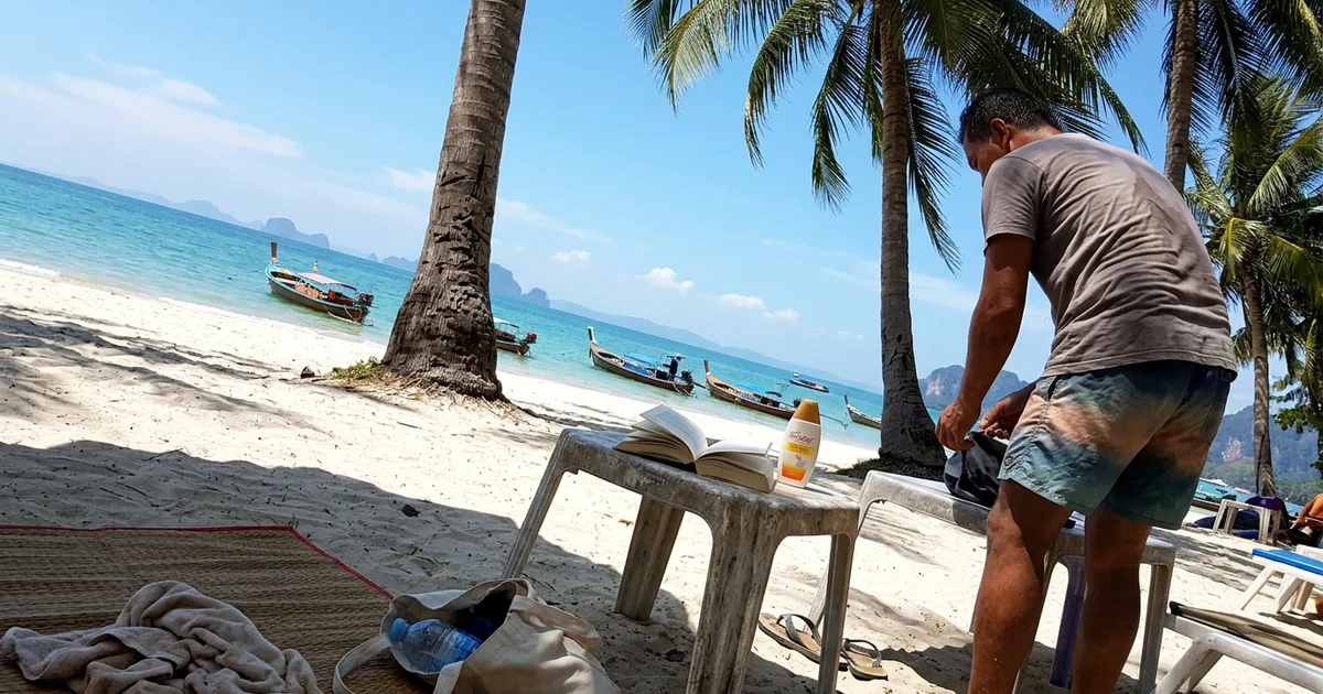 A clear blue sky over a southern Thai beach with palm trees and calm sea