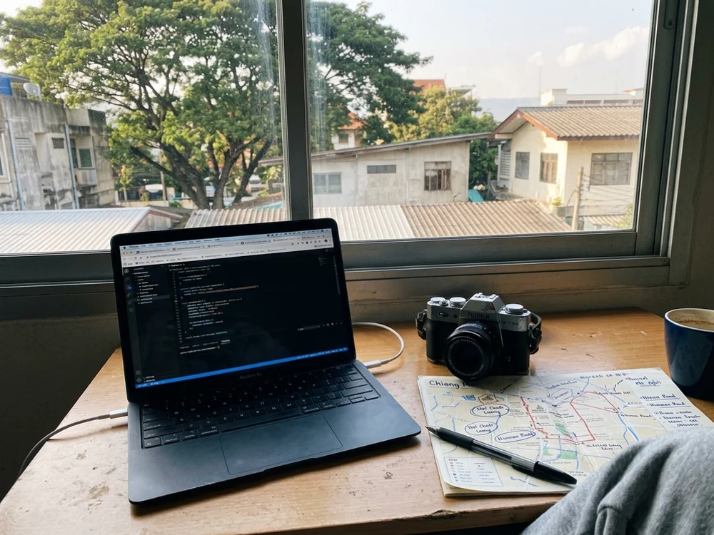 A desk with a laptop, camera and printed map of Chiang Mai