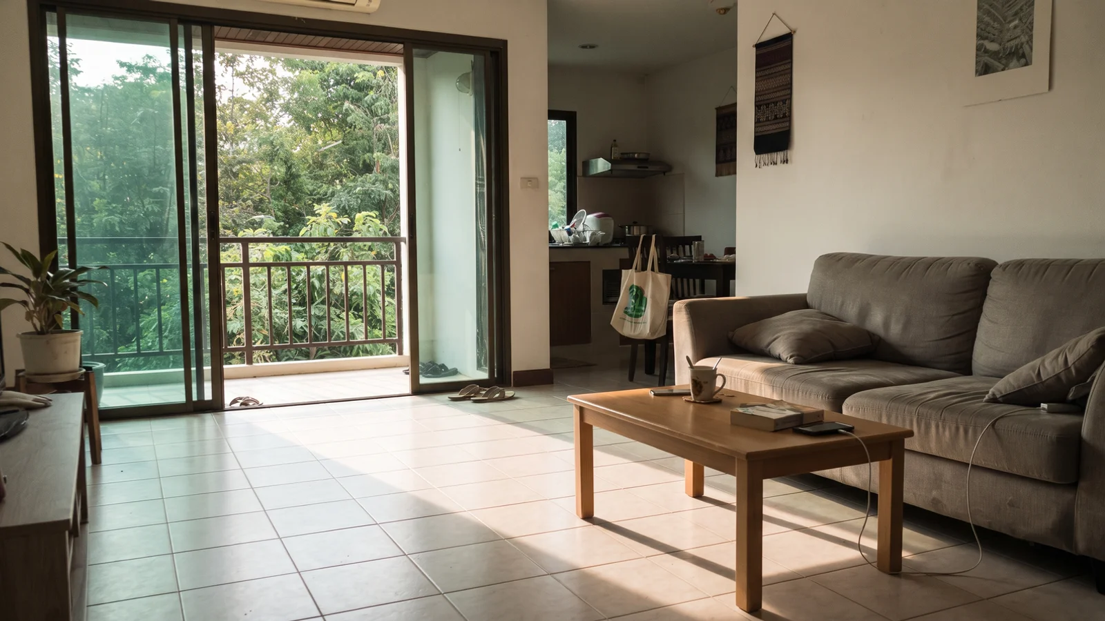 A furnished condo living room in Chiang Mai with balcony doors open to greenery